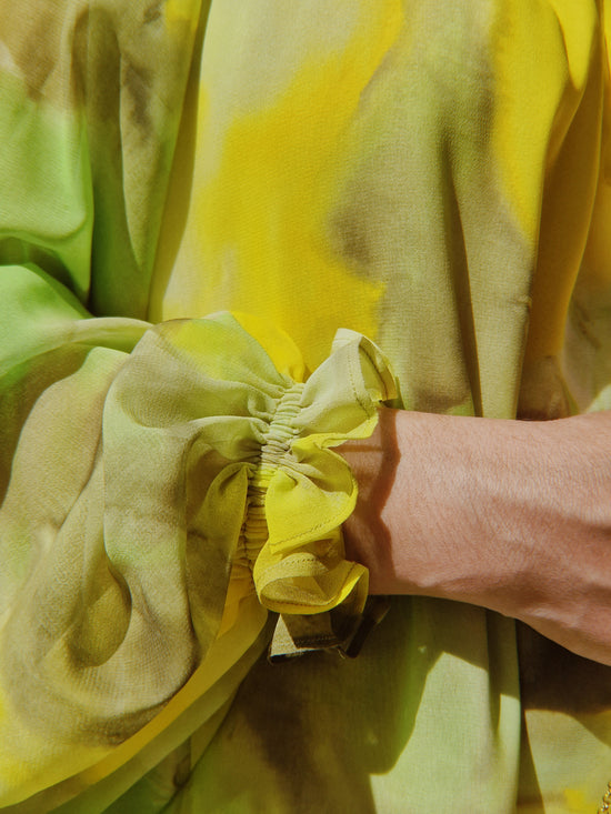 Detalle de manga del vestido vaporoso en tonos lima. Tiene la manga fruncida lo que eleva la elegancia del vestido para invitadas de primavera verano 2023